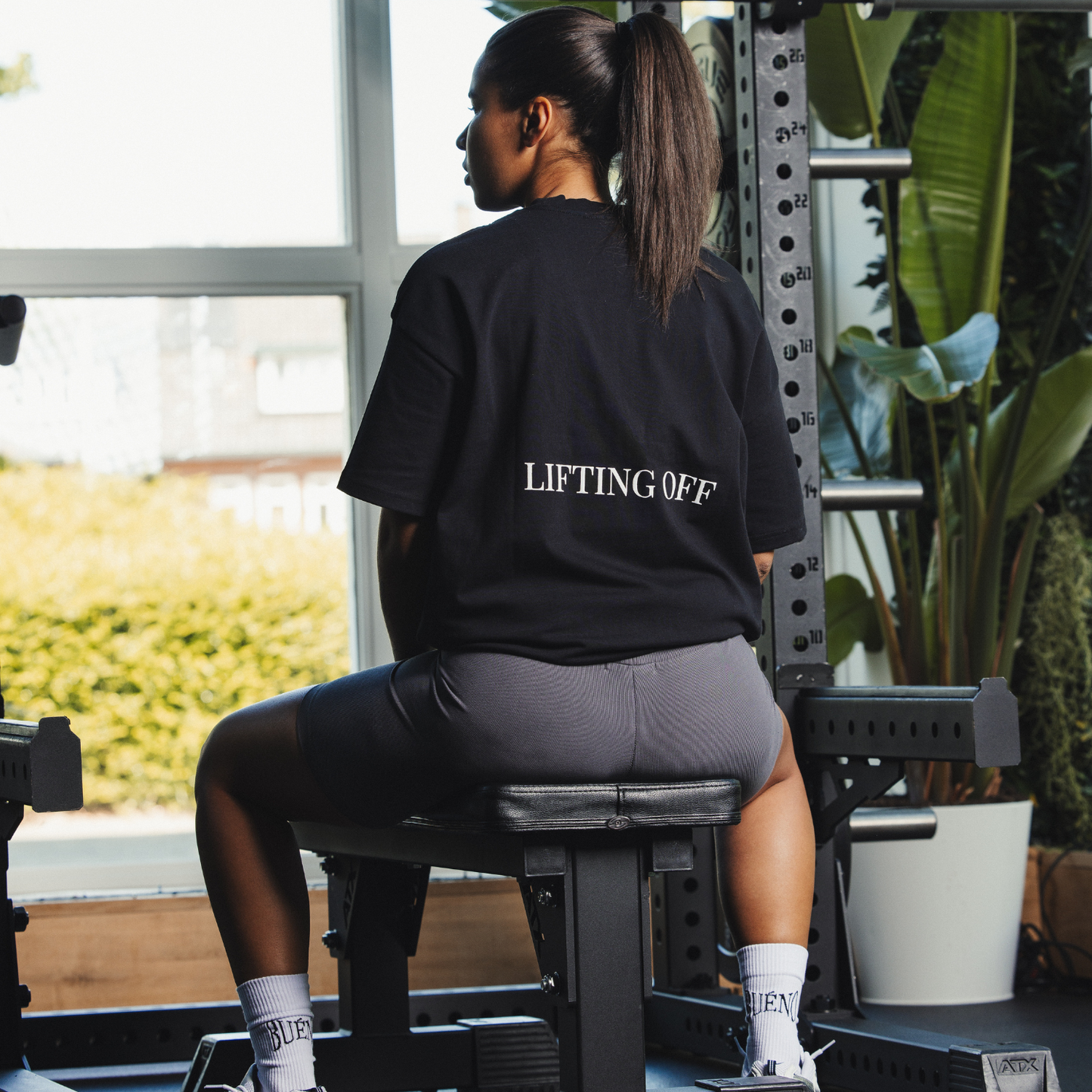 Person wearing a black 'LIFTING OFF' t-shirt in a gym setting